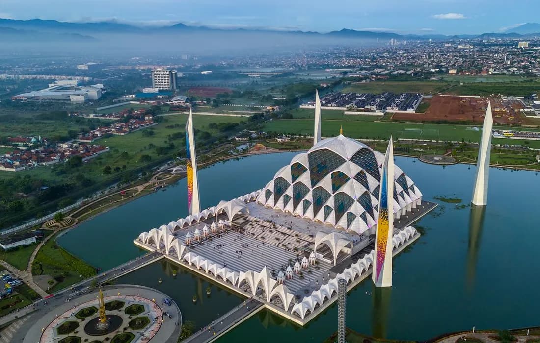 Pemandangan udara Masjid Raya Al Jabbar Bandung yang megah dengan arsitektur modern dan kubah besar, dikelilingi area hijau.