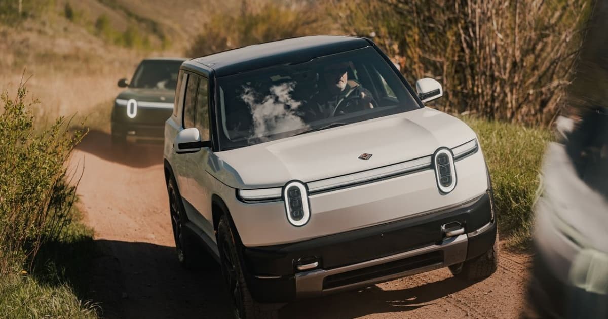 SUV listrik Rivian R2 berwarna hijau diparkir di luar ruangan dengan latar pegunungan