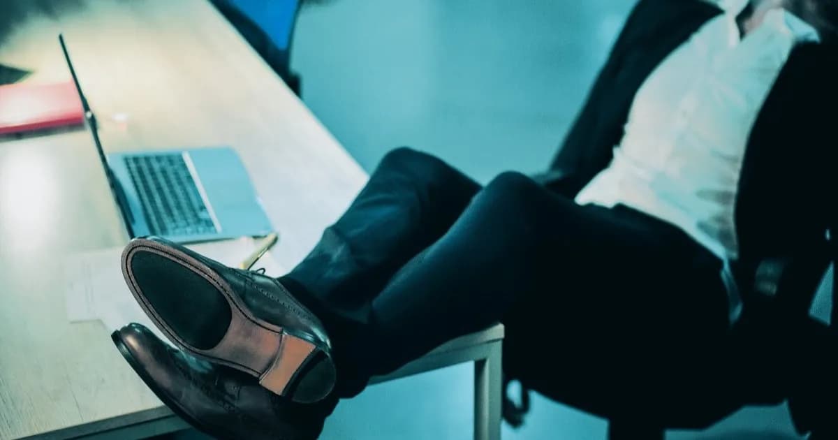 Kontraktor AI duduk santai di kantor dengan laptop terbuka di meja kayu