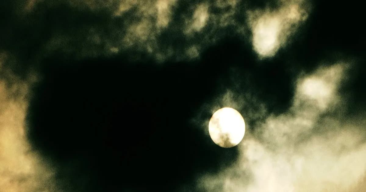 Foto matahari yang redup karena asap dan awan, ilustrasi konsep solar geoengineering.