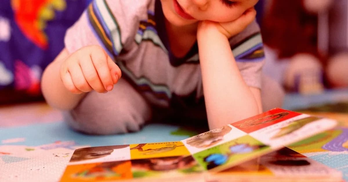 Seorang anak kecil sedang membaca buku bergambar di rumah