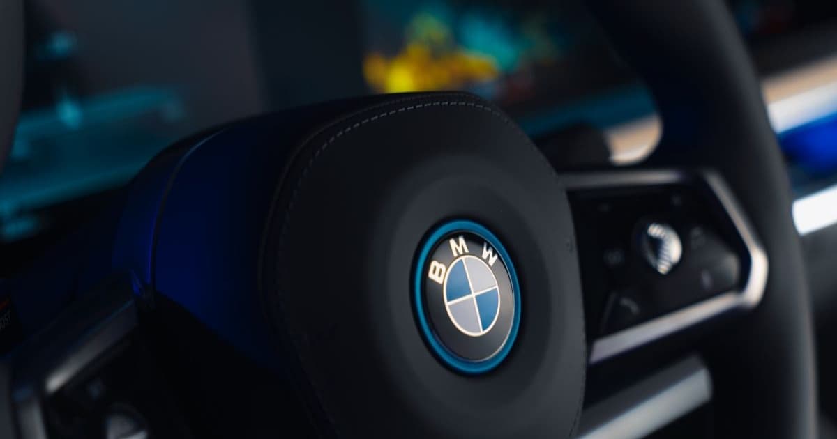 Logo BMW dengan latar belakang pabrik dan grafik penurunan laba
