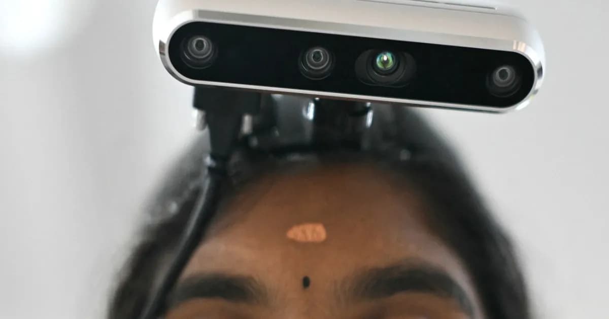 Pekerja garmen dengan kamera GoPro di kepala merekam gerakan tangan untuk data pelatihan robot humanoid di lantai pabrik India.