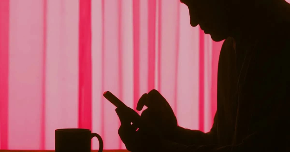 Siluet pria menggunakan smartphone dengan efek warna yang merepresentasikan kasus Grok Elon Musk hasilkan gambar eksplisit anak