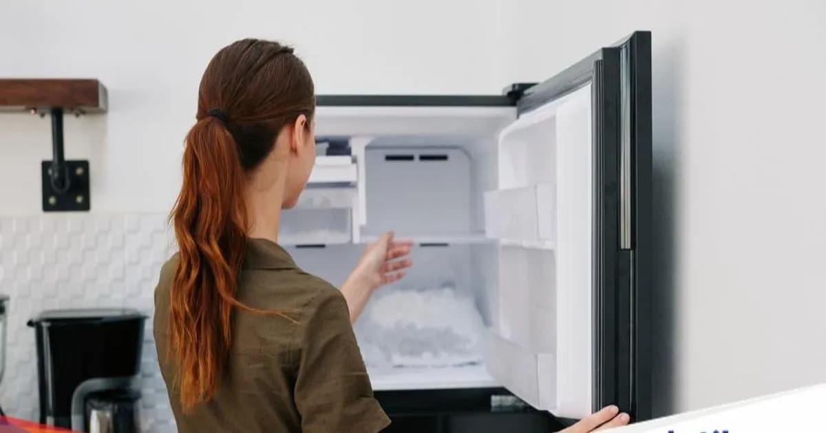 Ilustrasi kulkas dengan pintu terbuka, memperlihatkan rak kosong dan es di dalam freezer, latar belakang dapur rumah